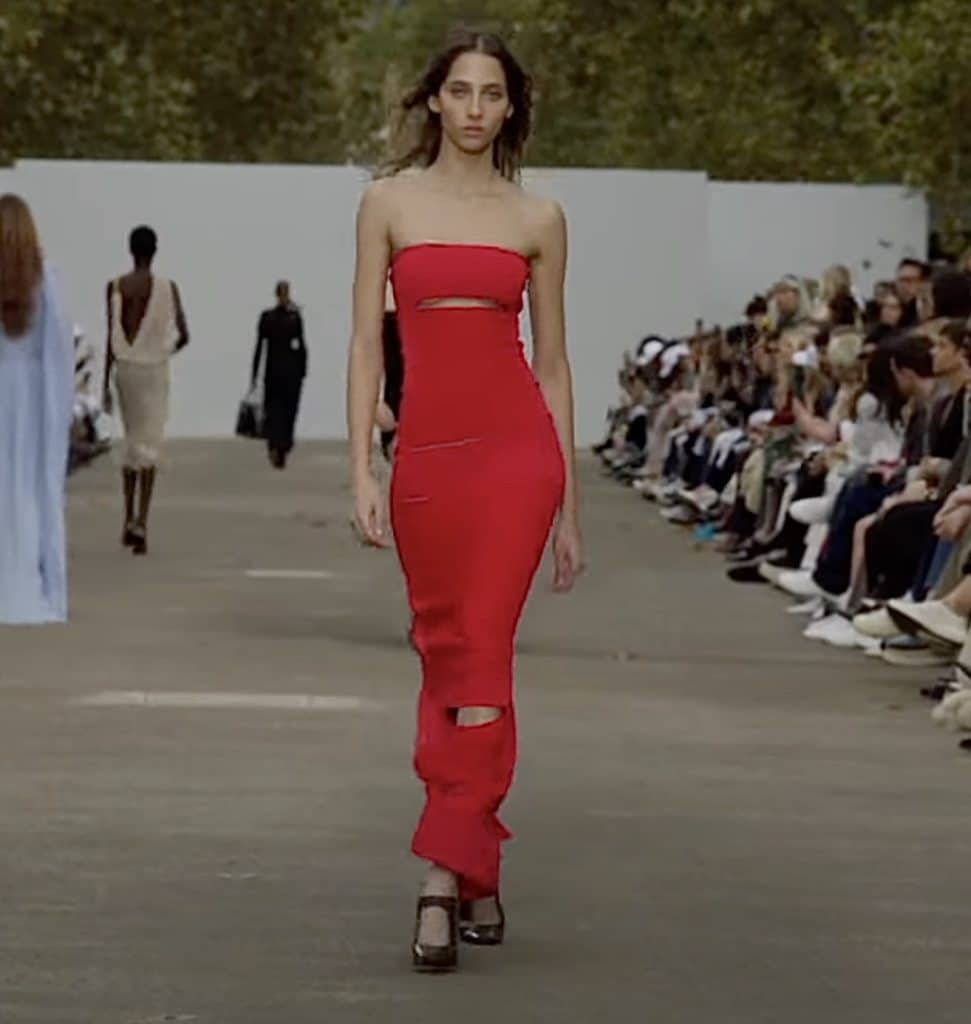model walking down the runway wearing long red dress with cutouts
